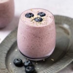 A glass filled with low-calorie protein shake, garnished with fresh blueberries.