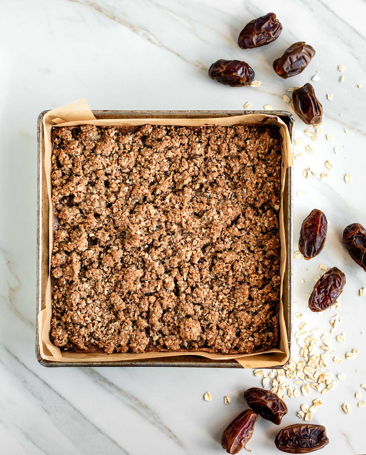 Baking pan filled with golden-brown oatmeal date bars ready to be cut