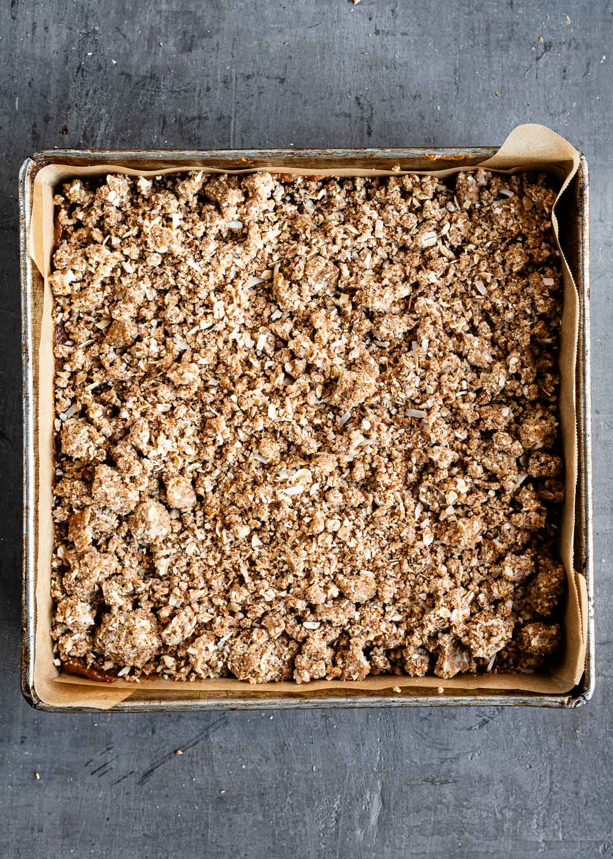 A crumbly layer added as a top layer to a square baking dish for date bars