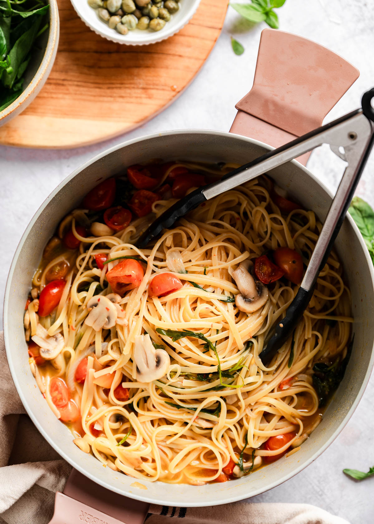 Metal tongs laying in a pot with freshly cooked pasta