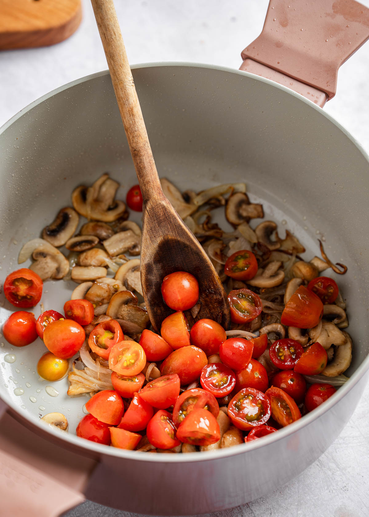 Cherry tomatoes and cooked mushrooms in a pot