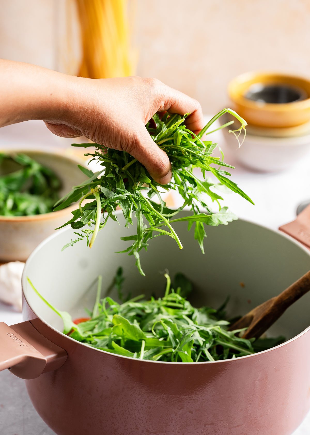 A person adding arugula in pot