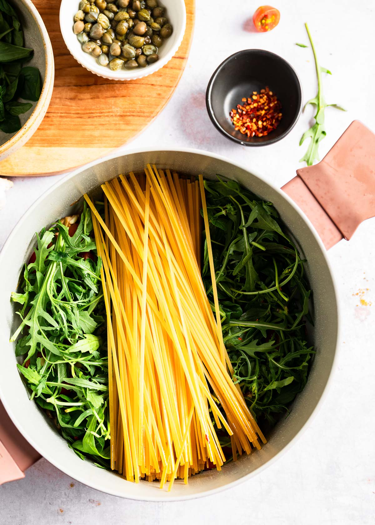 A bundle of long pasta resting on a fresh layer of arugula 