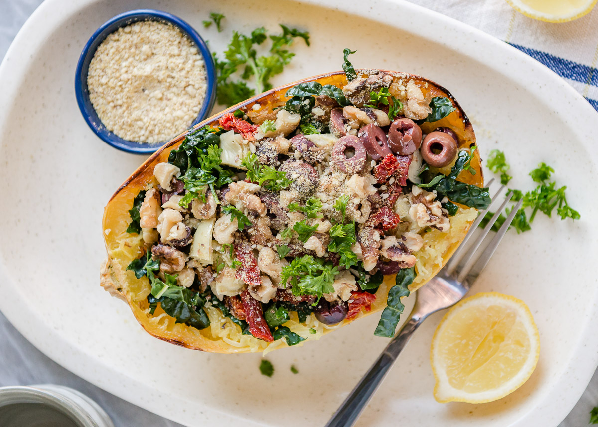 Baked spaghetti squash on a plate with lemon and vegan parmesan cheese