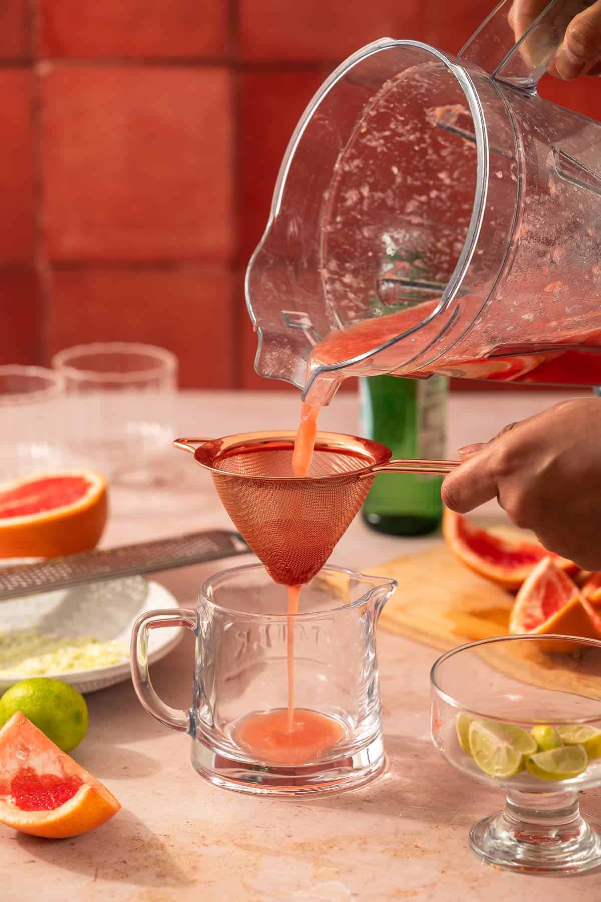 Blended paloma mixture being poured through a fine-mesh strainer
