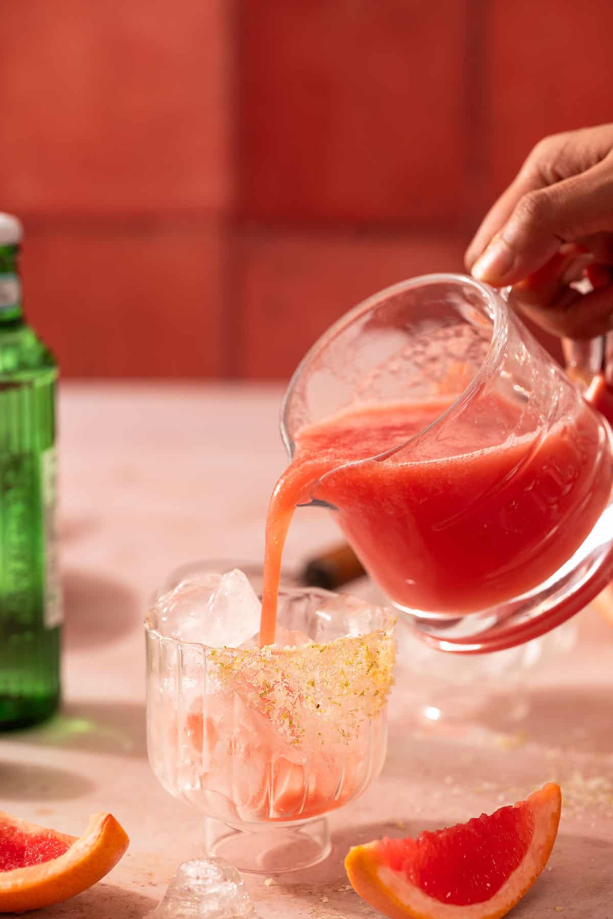 Pouring paloma juice into a serving glass
