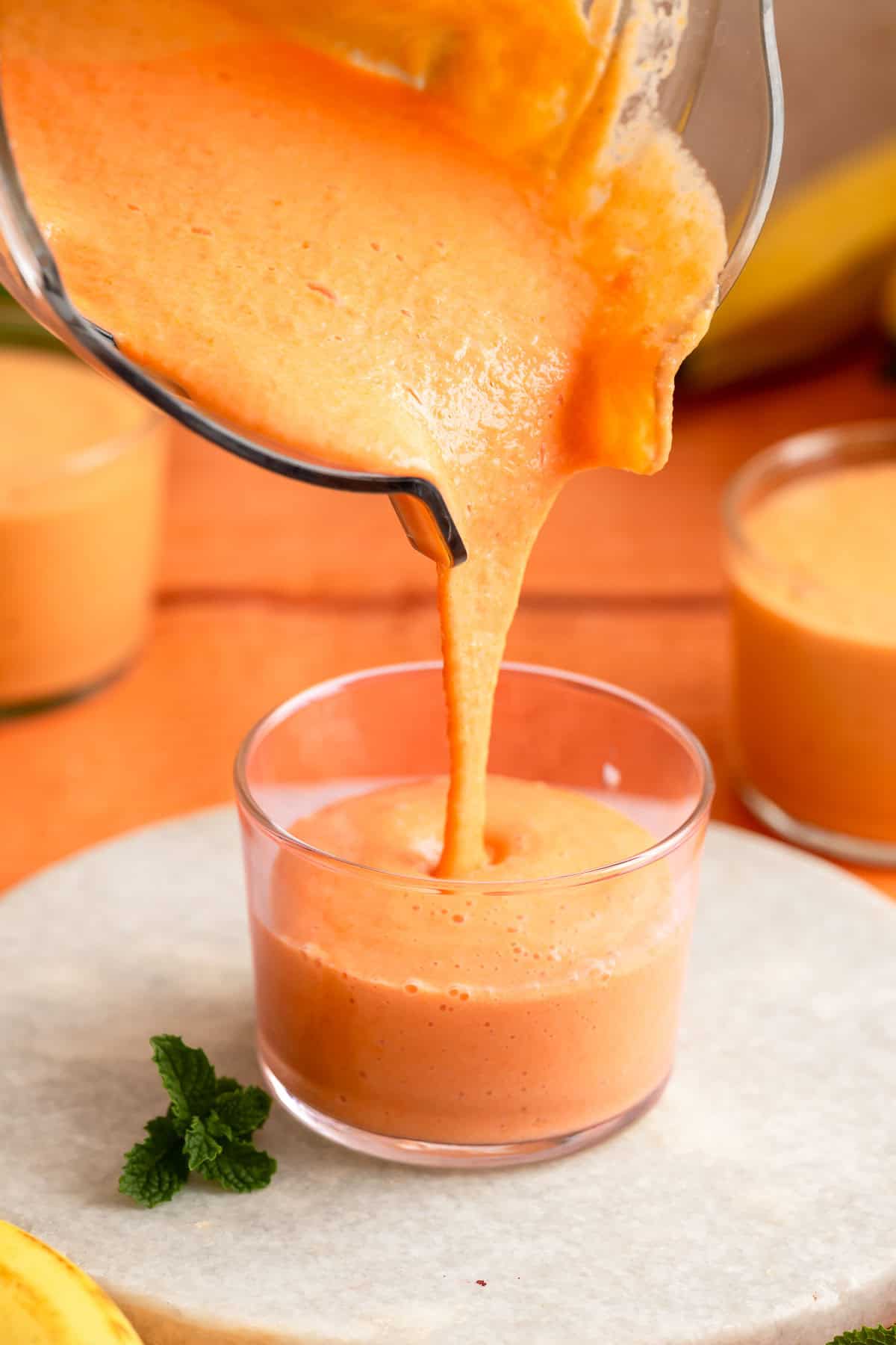 Fresh papaya banana smoothie being poured into a glass