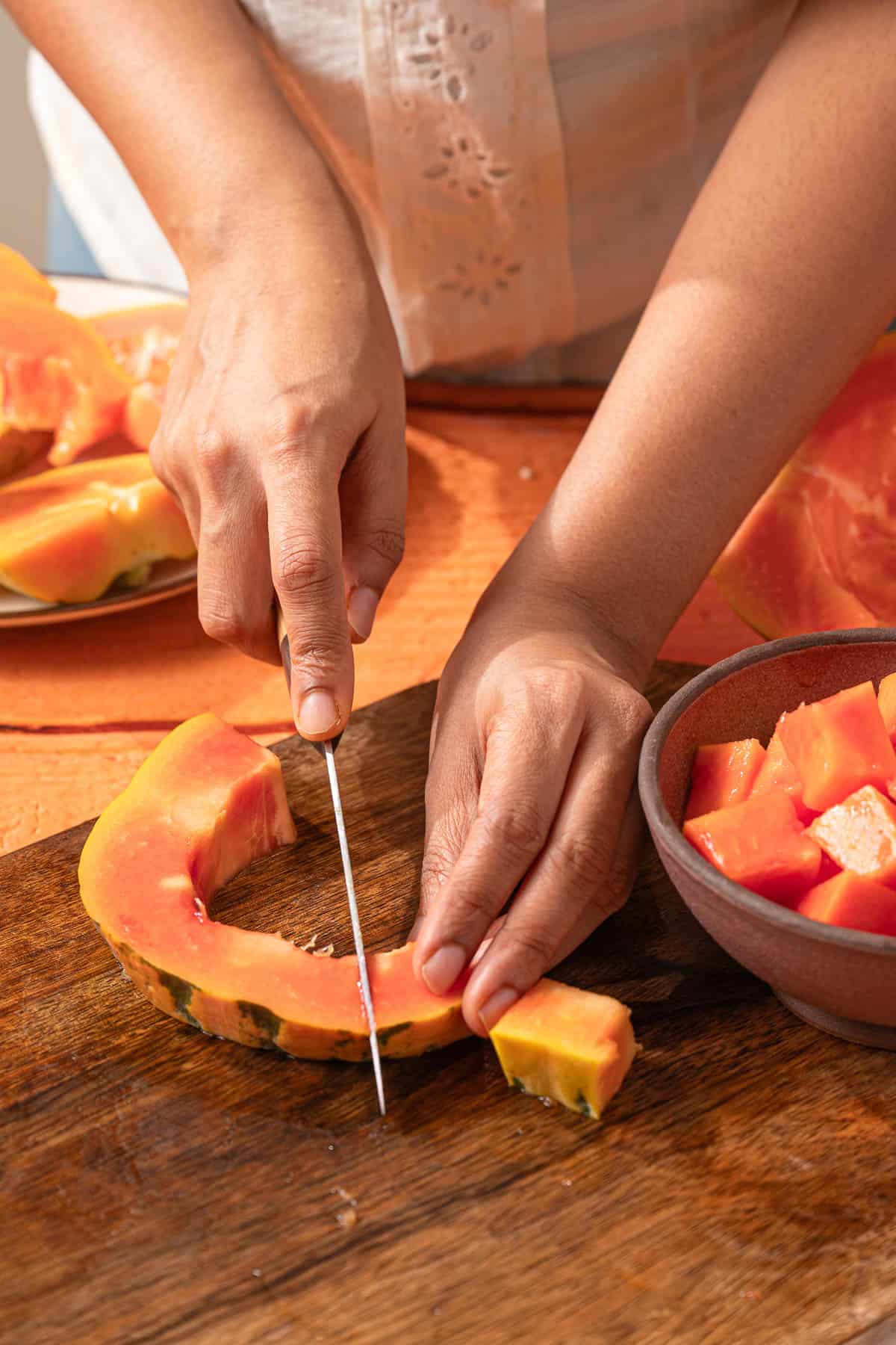 Slicing fresh papaya on a wooden cutting board