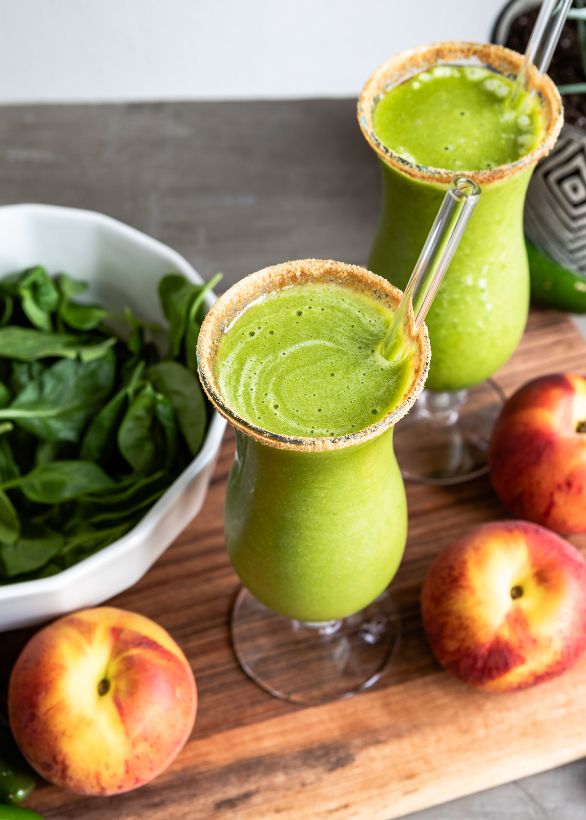 Two probiotic smoothies in cocktail glasses, rimmed with coconut sugar, and served with glass straws.