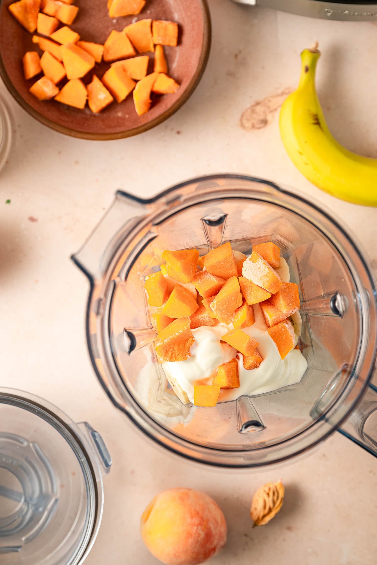 Frozen peaches, banana slices, diced sweet potatoes, and Greek yogurt in a blender