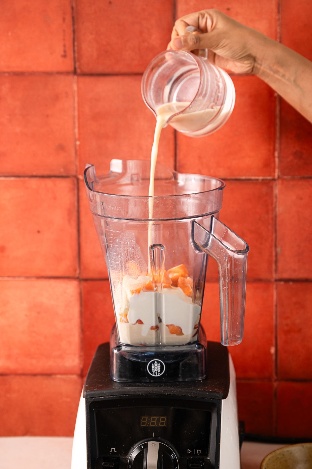 Adding oat milk to the blender