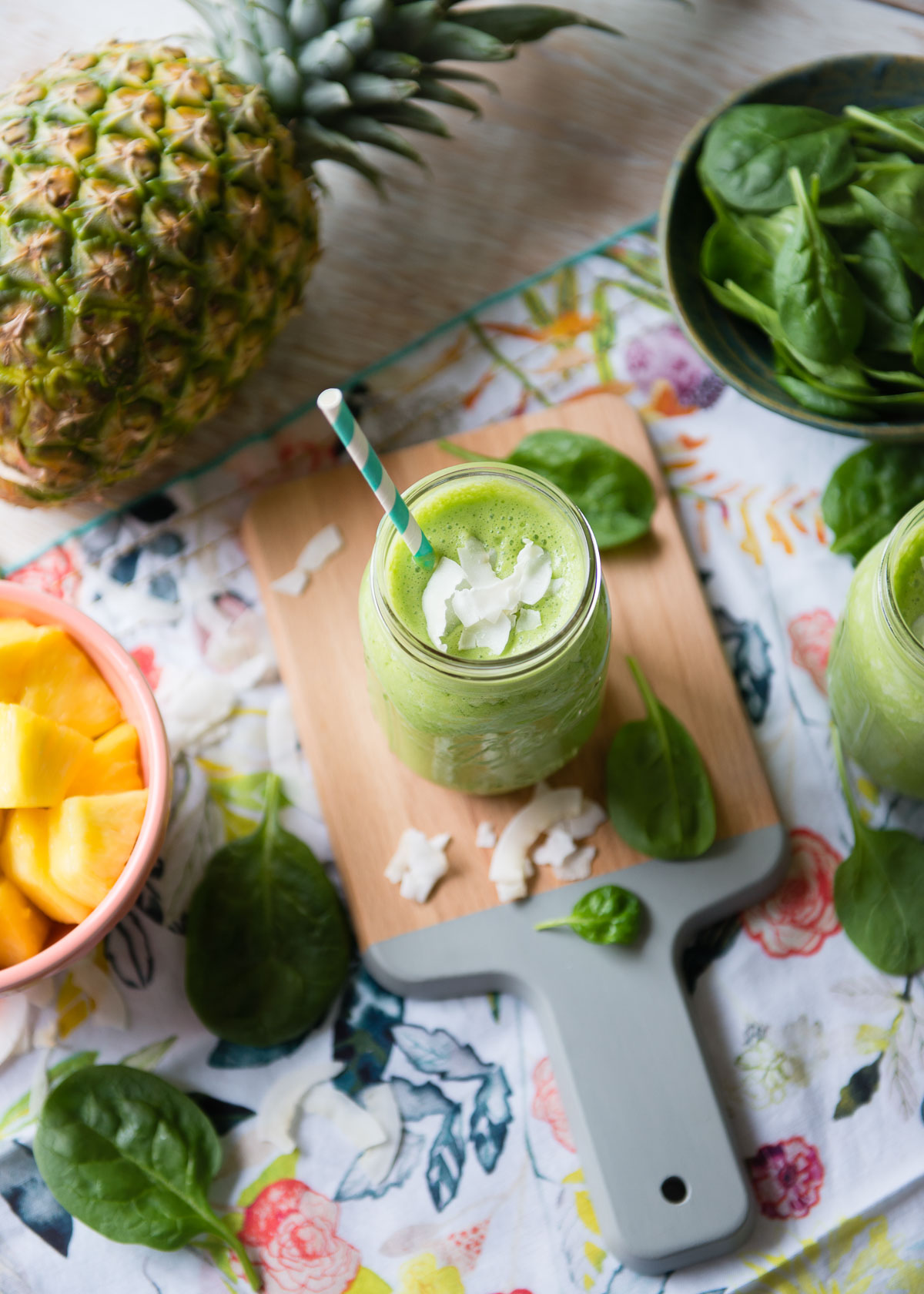 Overhead view of a Piña Colada smoothie garnished with coconut flakes, surrounded by its ingredients on a table.