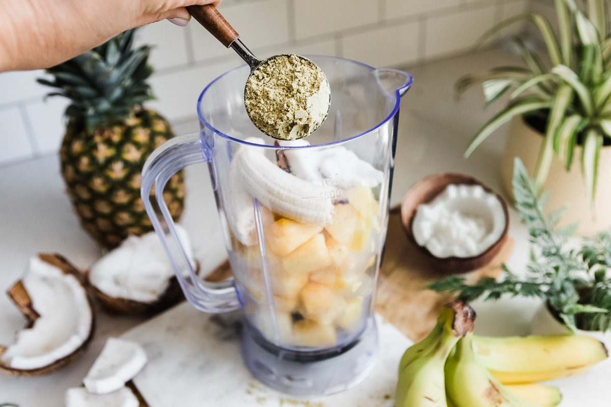 Frozen pineapple chunks and unpeeled bananas inside a blender, ready to be blended