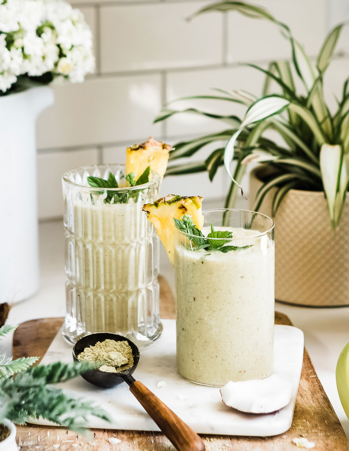 Glass of pineapple banana smoothie topped with a chunk of fresh pineapple on the rim