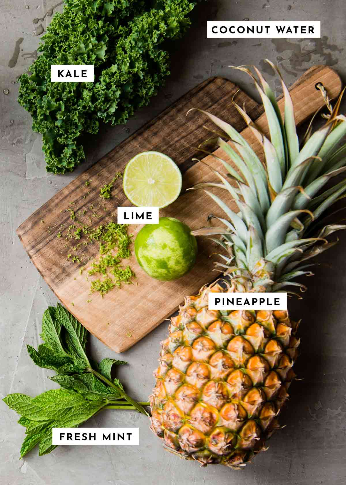 ingredients for a tropical smoothie recipe including pineapple, lime, mint and kale.