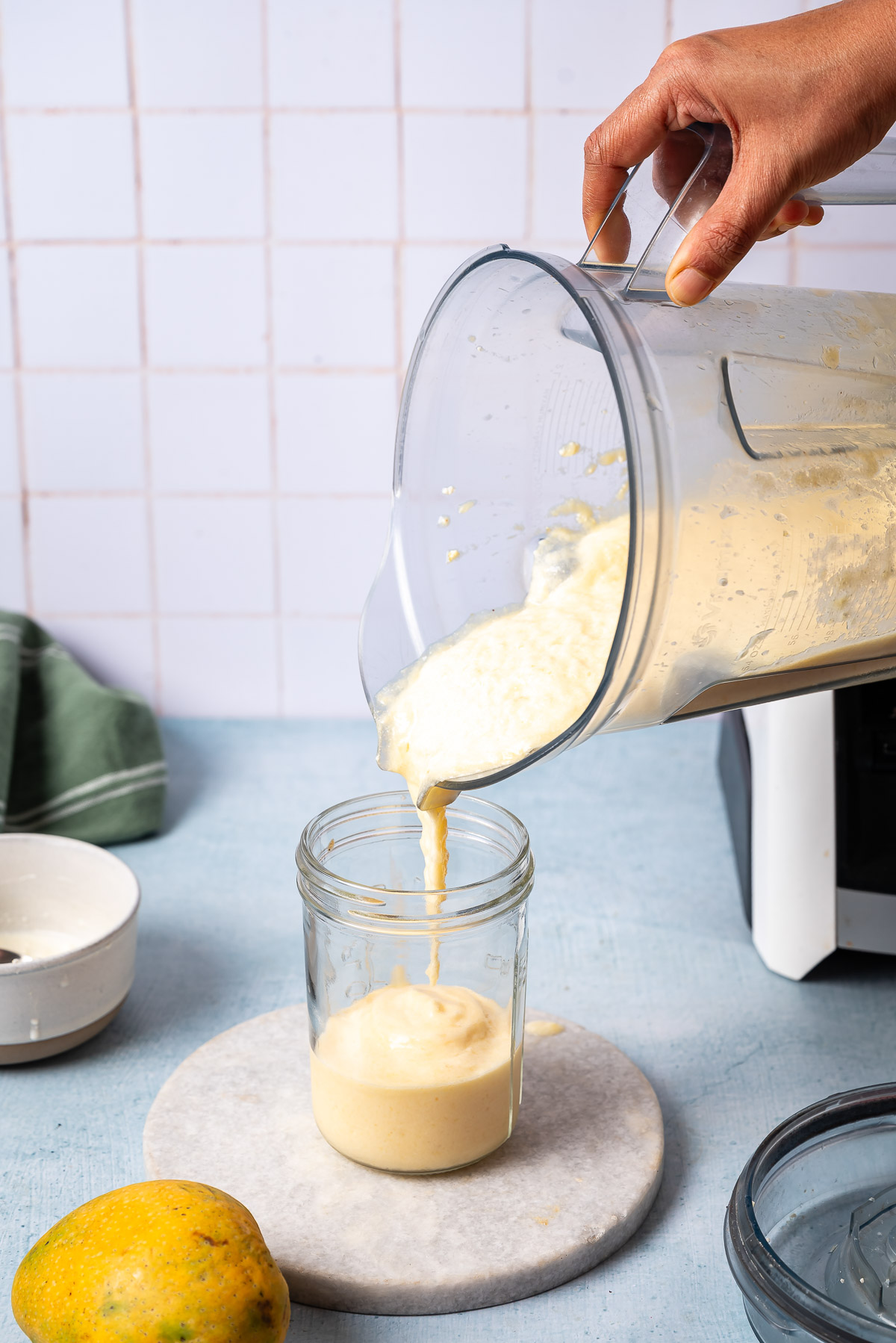 A person adding pineapple cottage cheese smoothie in a glass
