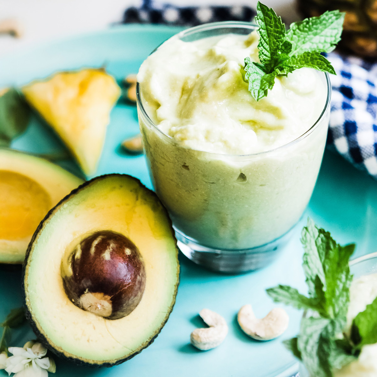 A cut avocado next to an avocado smoothie garnished with fresh mint
