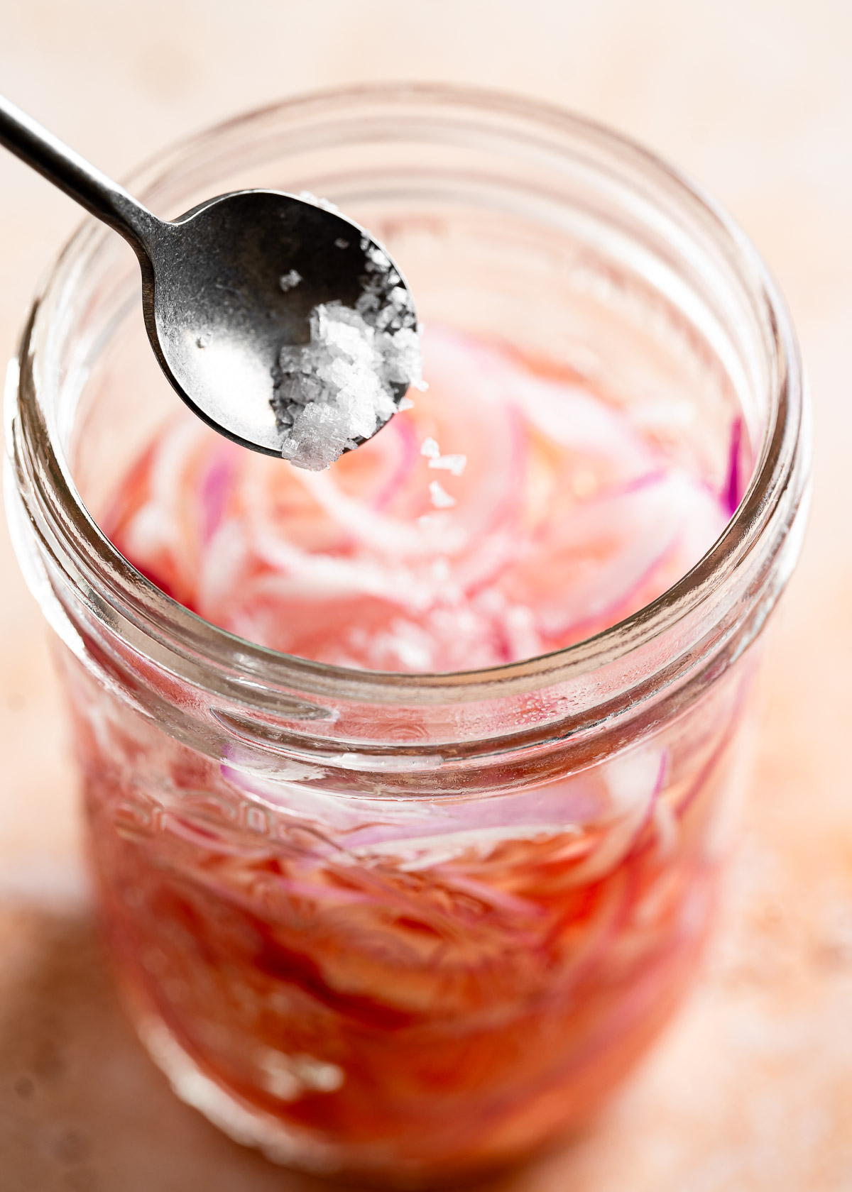 Adding a teaspoon of salt into a jar filled with sliced onions and water