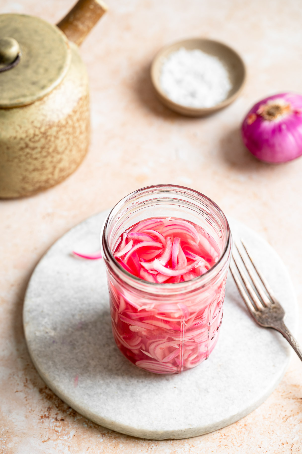 Glass jar filled with vibrant pink pickled red onion slices