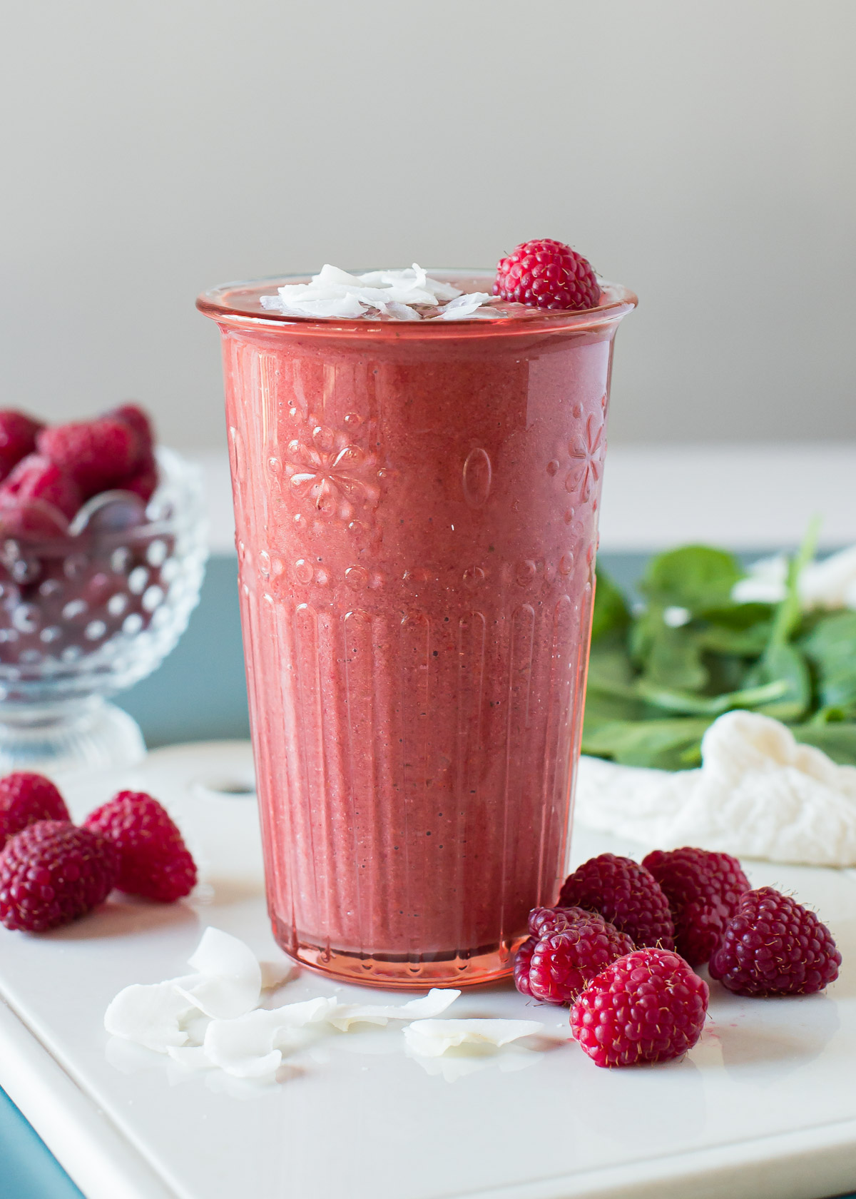 Raspberry smoothie in a glass, surrounded by raspberries