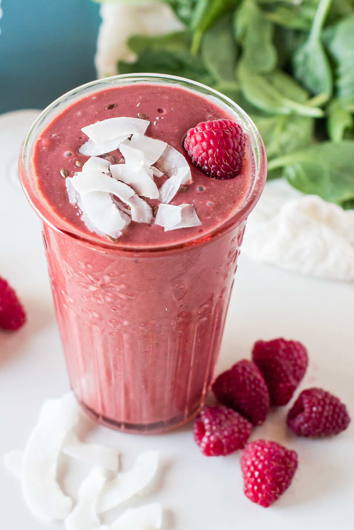 Raspberry smoothie in a glass, surrounded by raspberries