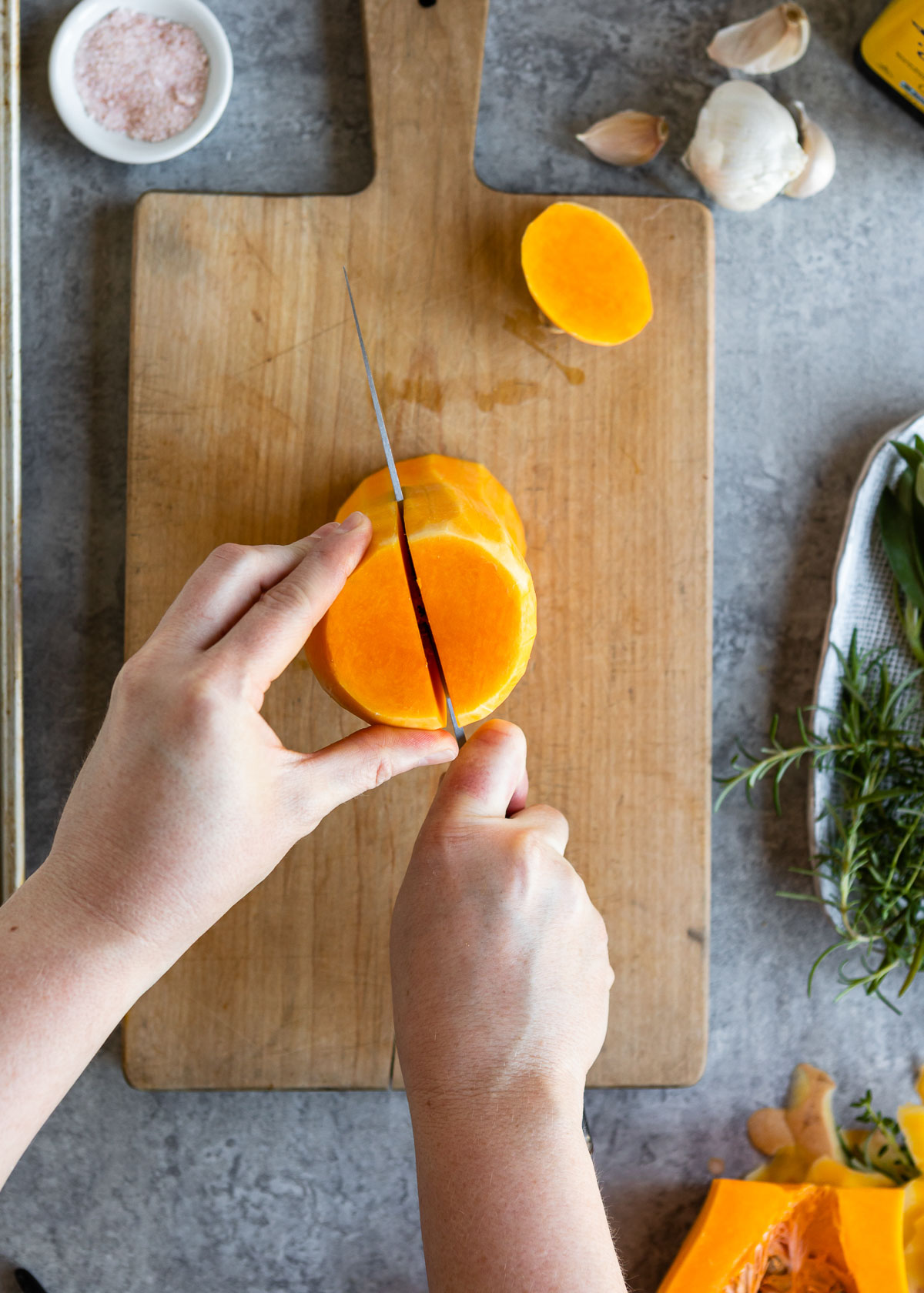 A person slicing butternut squash in halve