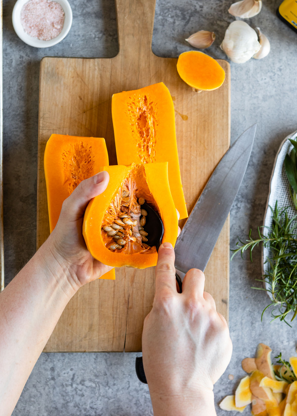 A person scooping out seeds from butternut squash