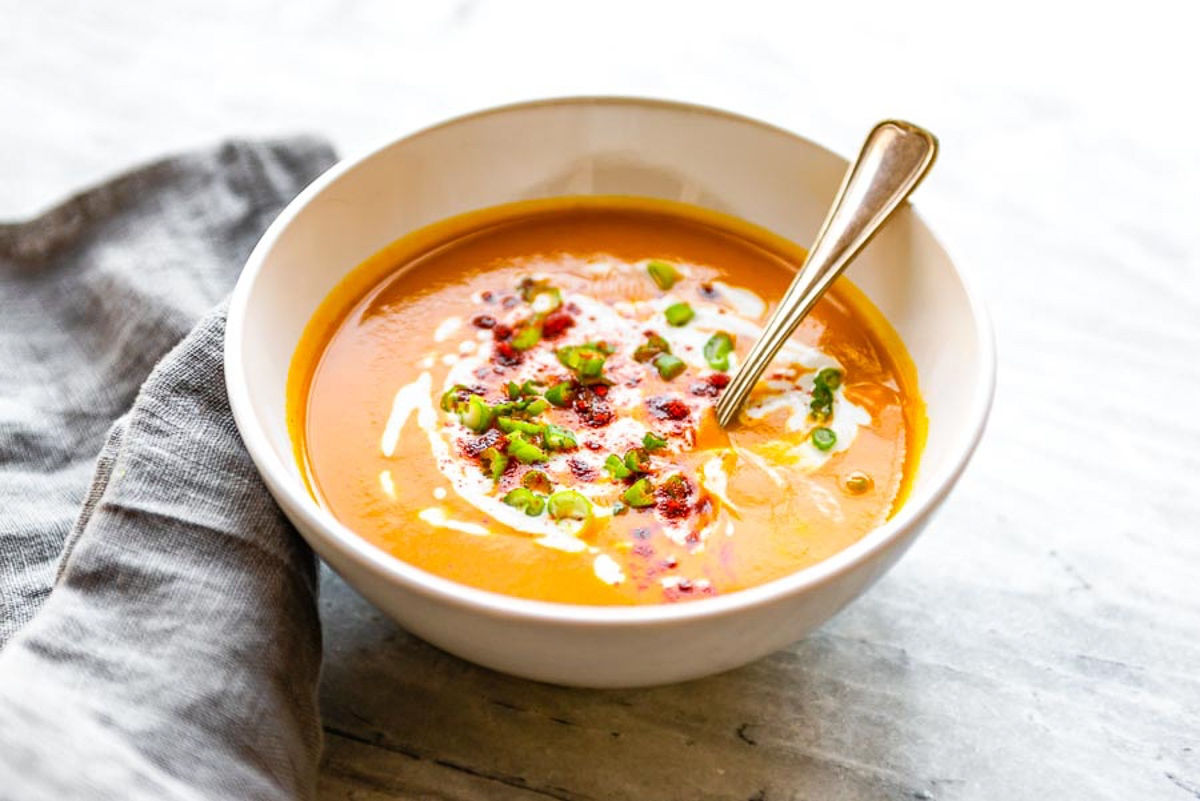 Roasted red pepper soup topped with cream, cayenne, and chopped green chili