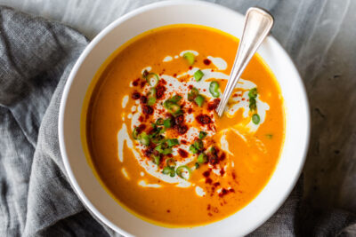 Roasted red pepper vegan soup in a bowl with a spoon