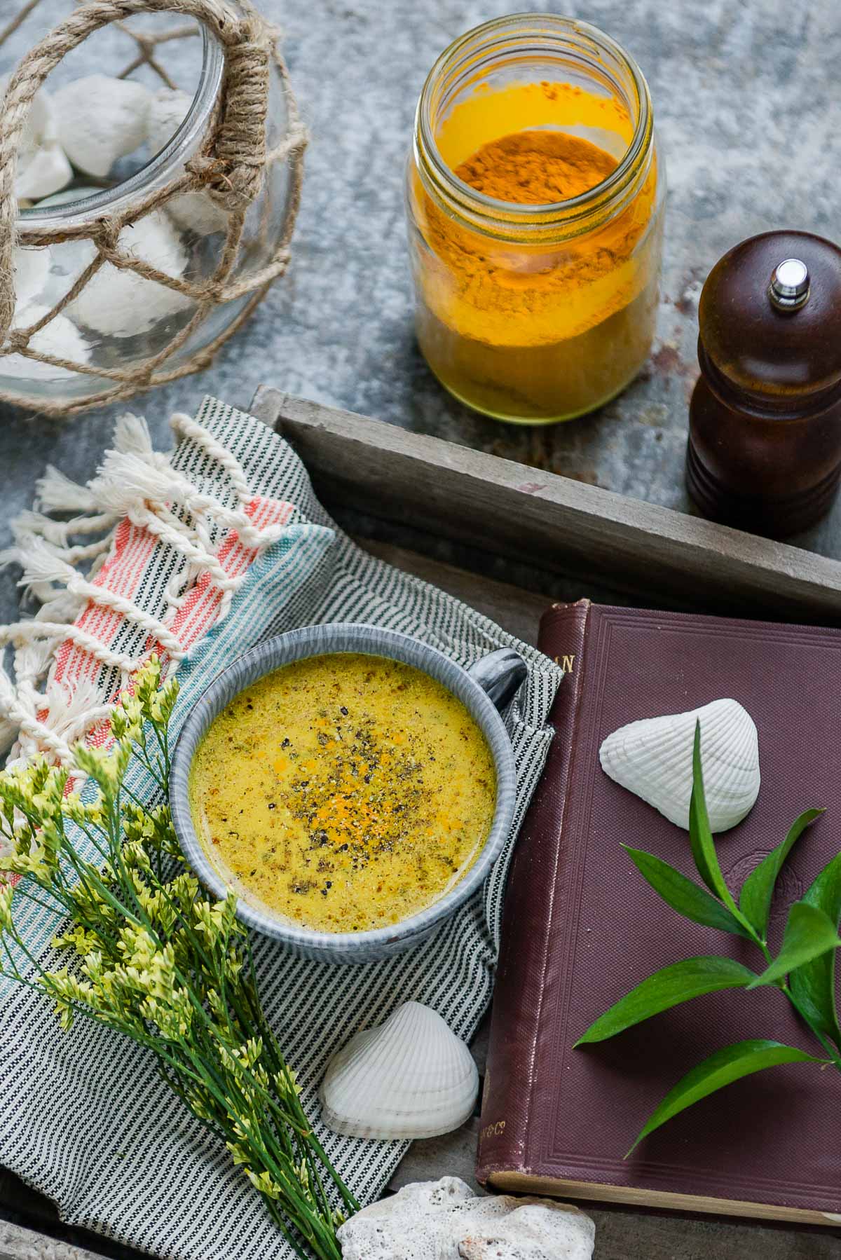 Warm cup of golden milk recipe and a jar of turmeric powder
