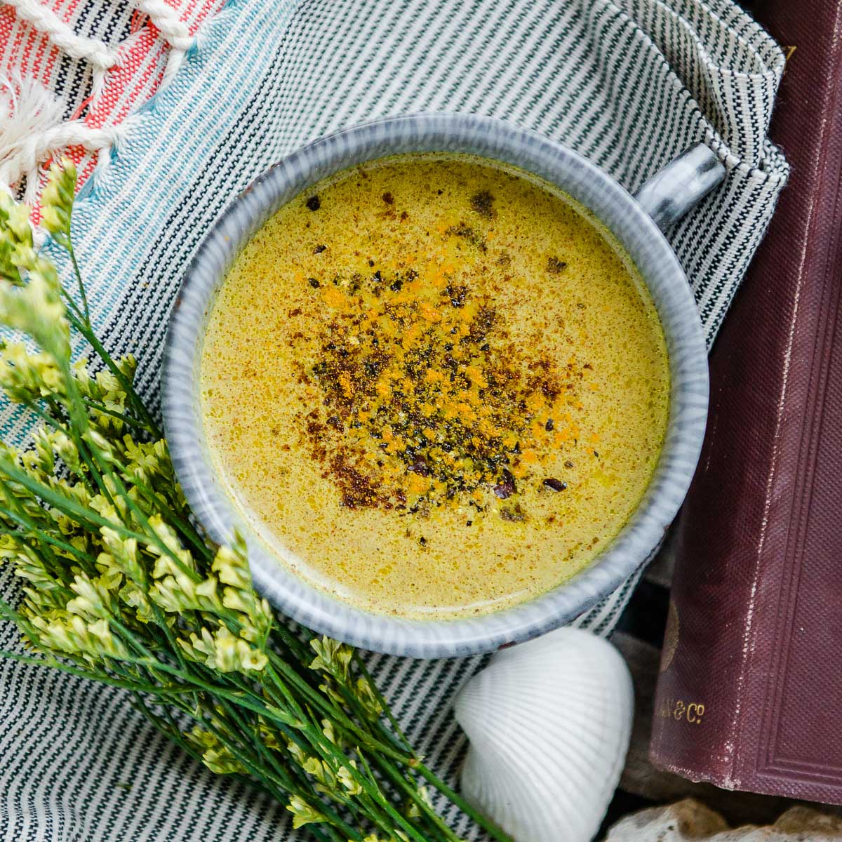 A warm cup of golden milk recipe topped with a sprinkle of cinnamon