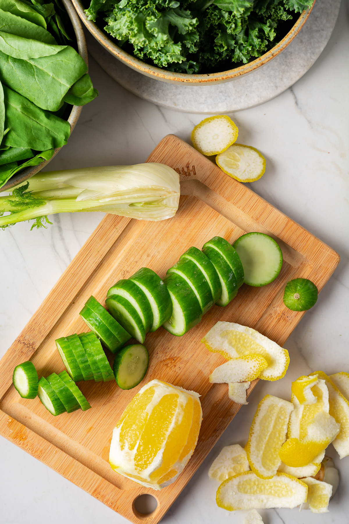 Chopped cucumbers and a peeled lemon on a cutting board