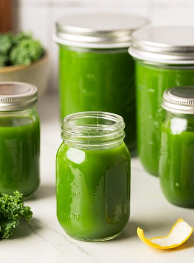 Glass jars filled with green juice recipe and sealed with lids