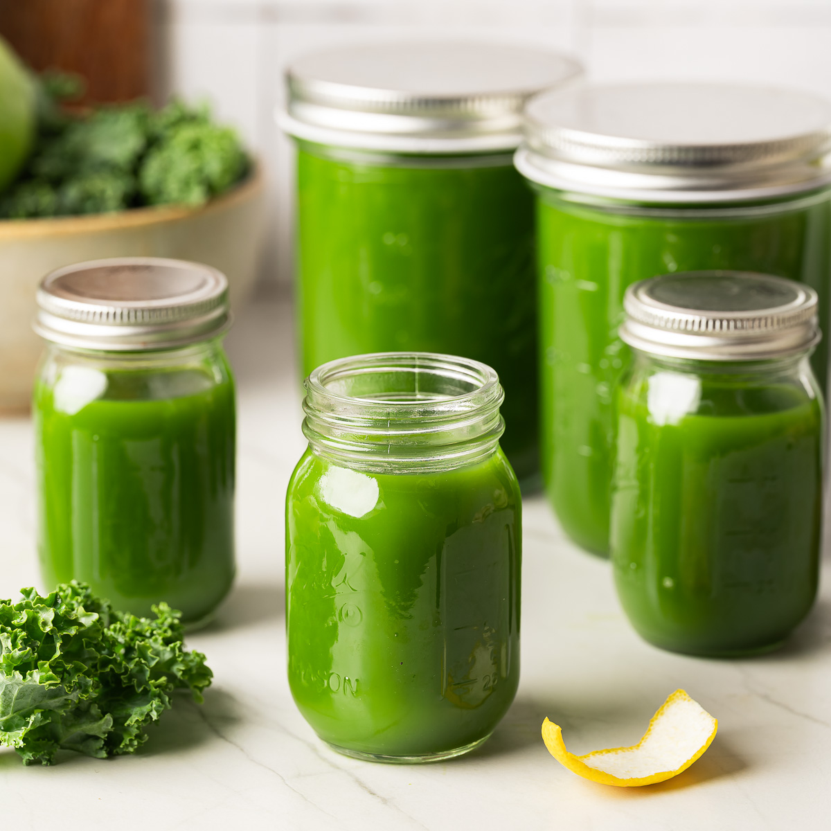 Glass jars filled with green juice recipe and sealed with lids
