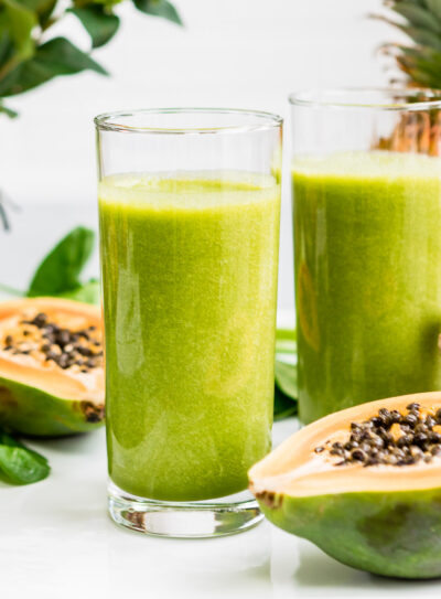 Two tall glasses of creamy papaya spinach smoothie.