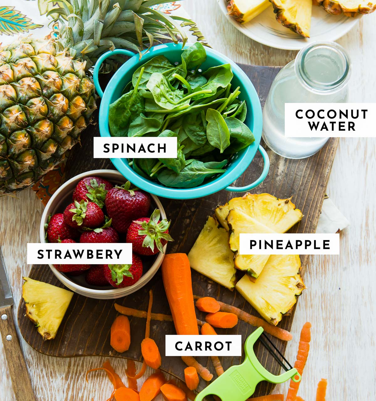Ingredients for a Strawberry carrot smoothie: pineapple, coconut water, spinach, strawberries, and carrots.