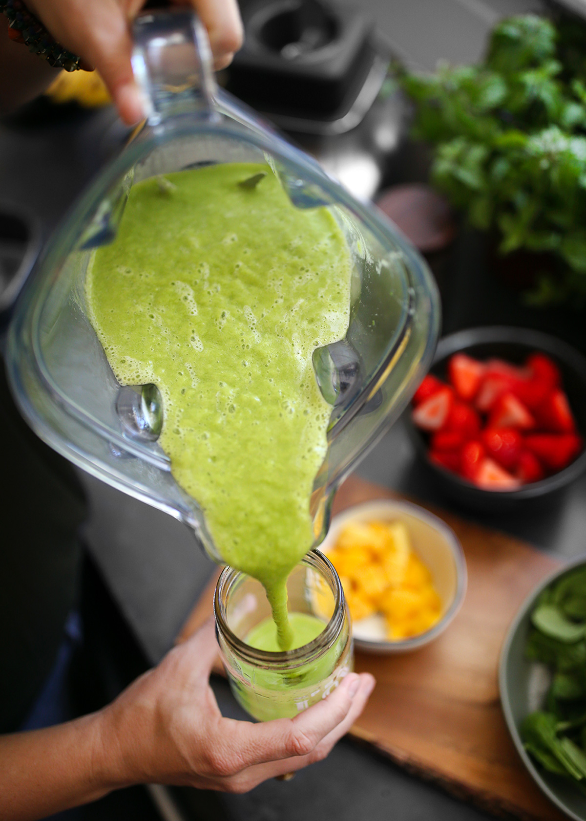 Pouring a strawberry mango smoothie into a glass Mason jar.
