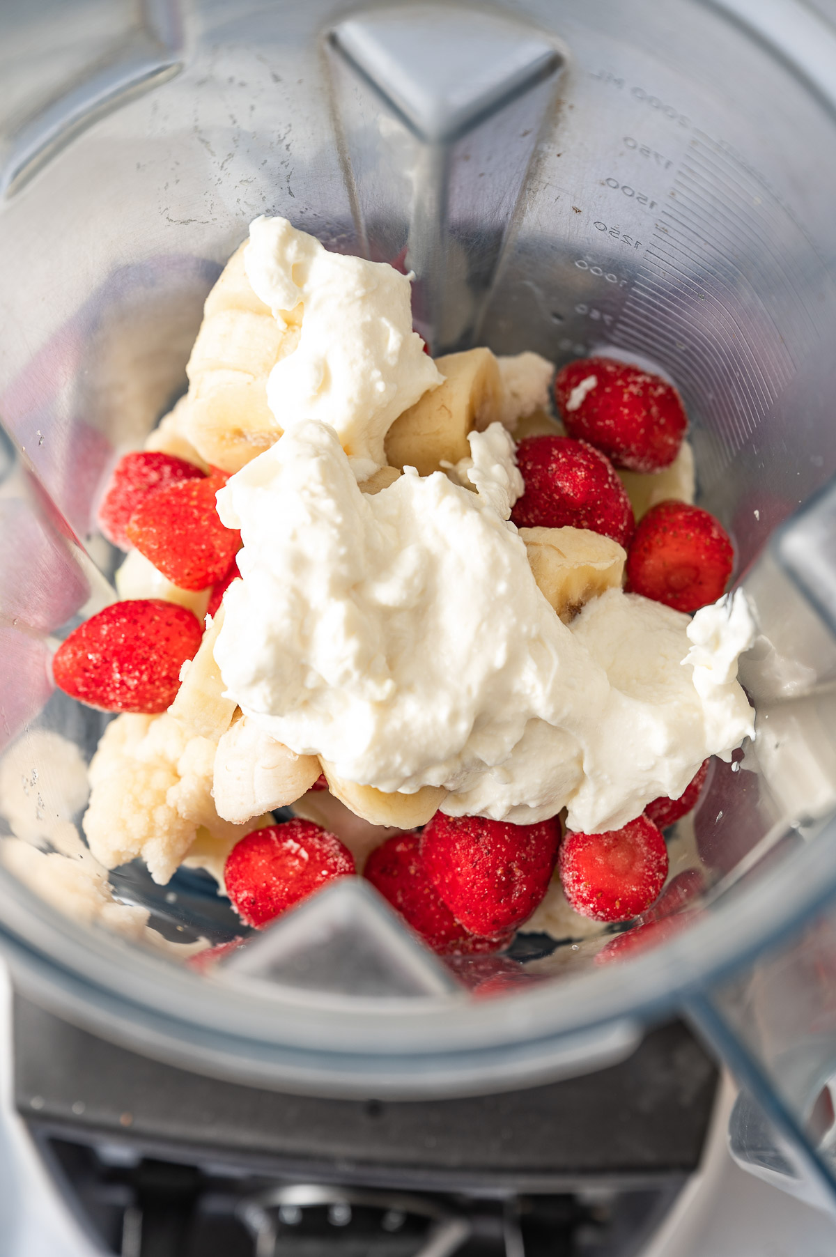 A blender containing fruits and Greek yogurt