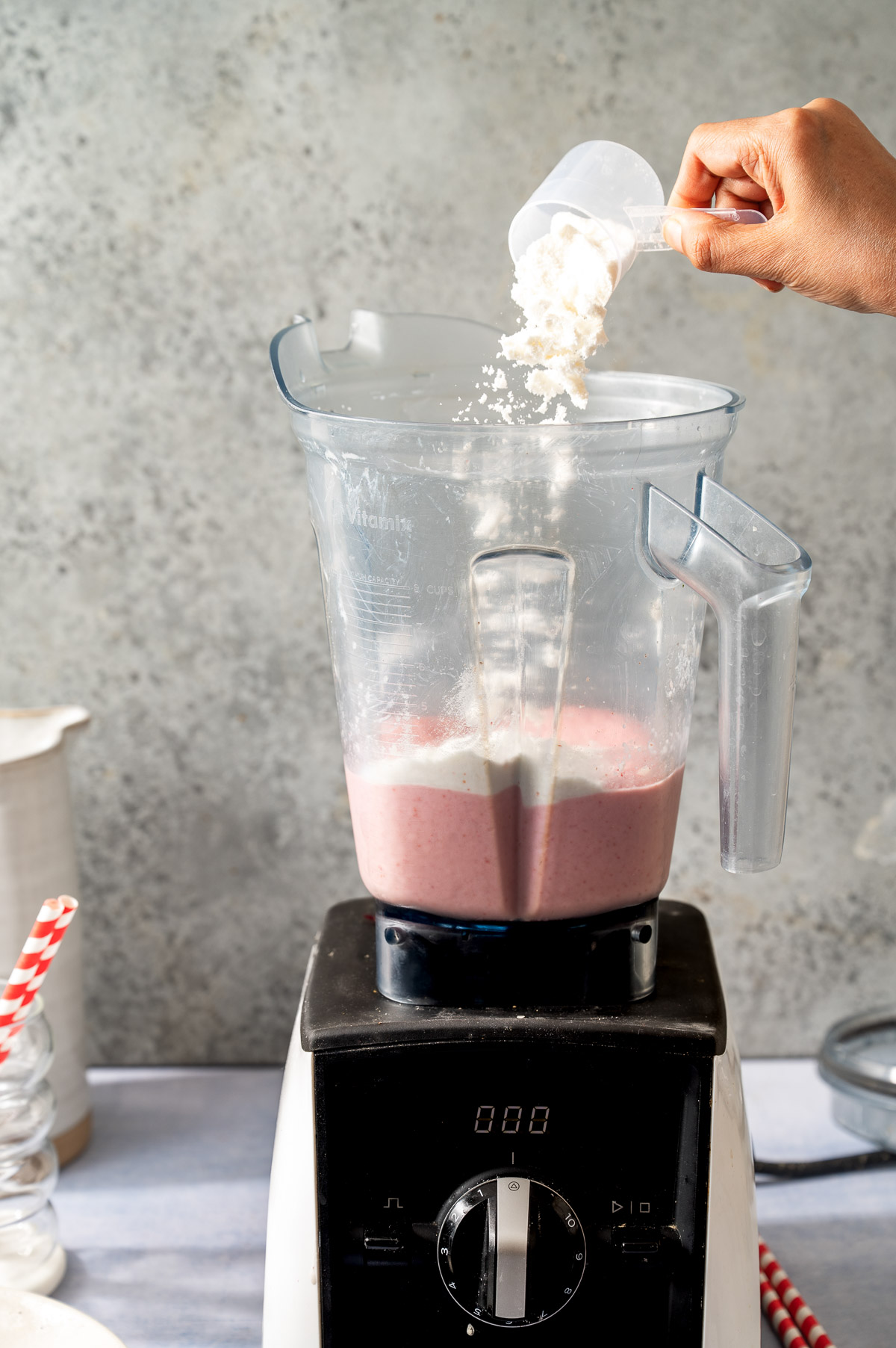 A person adding protein powder in a blender