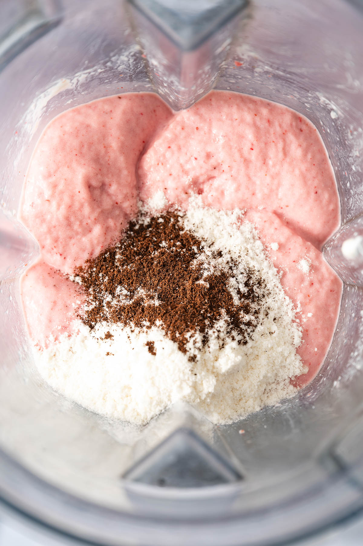 A protein shake mixture with protein powder and vanilla bean powder on top