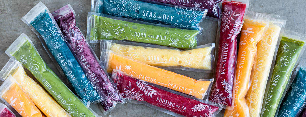 colorful homemade popsicles in plastic sleeves on a grey countertop