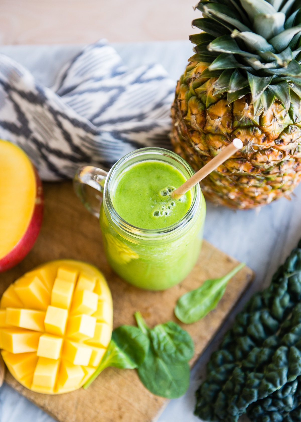 Detox smoothie in a mason jar with a paper straw Surrounded by fresh ingredients.
