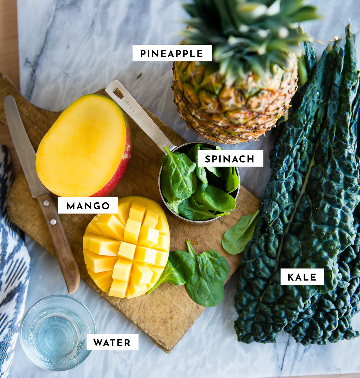 Label ingredients for tropical detox smoothie, including pineapple reacted. Please stop, spinach, mango, kale and water.