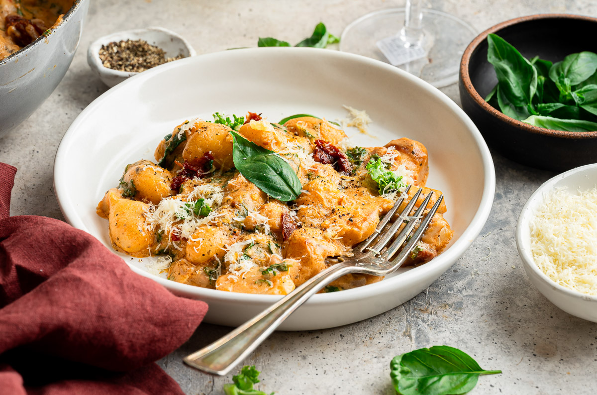Tuscan vegan gnocchi, topped with fresh basil and vegan parmesan
