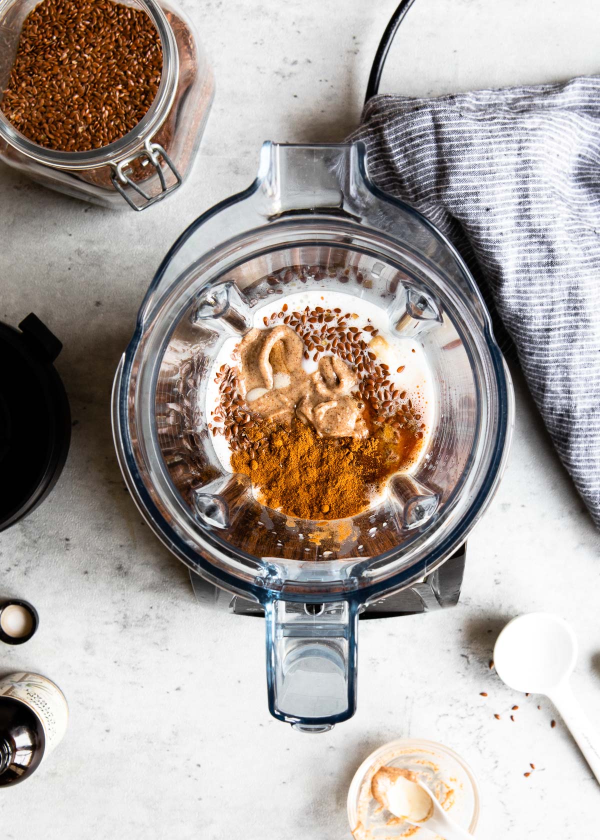 A blender container filled with almond milk, flaxseed, and cinnamon