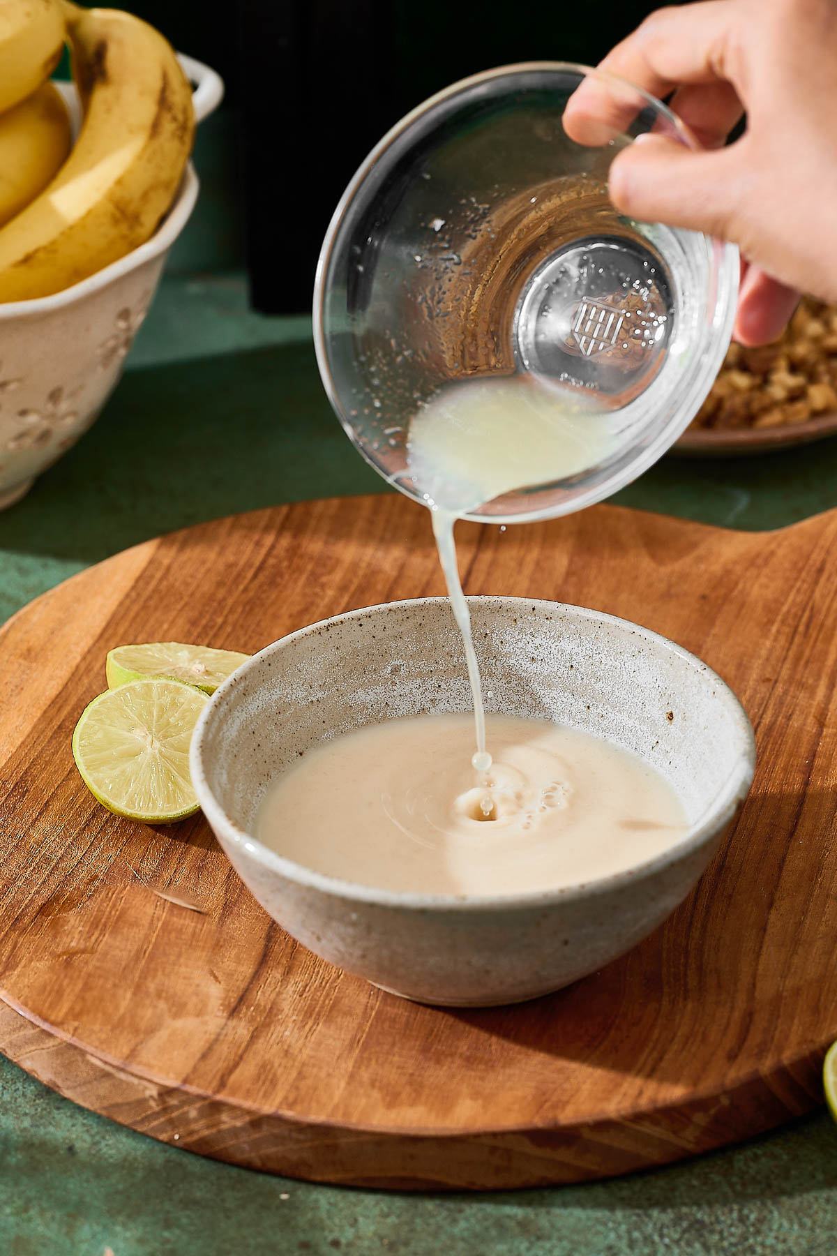 Pouring lemon juice in a bowl of oat milk