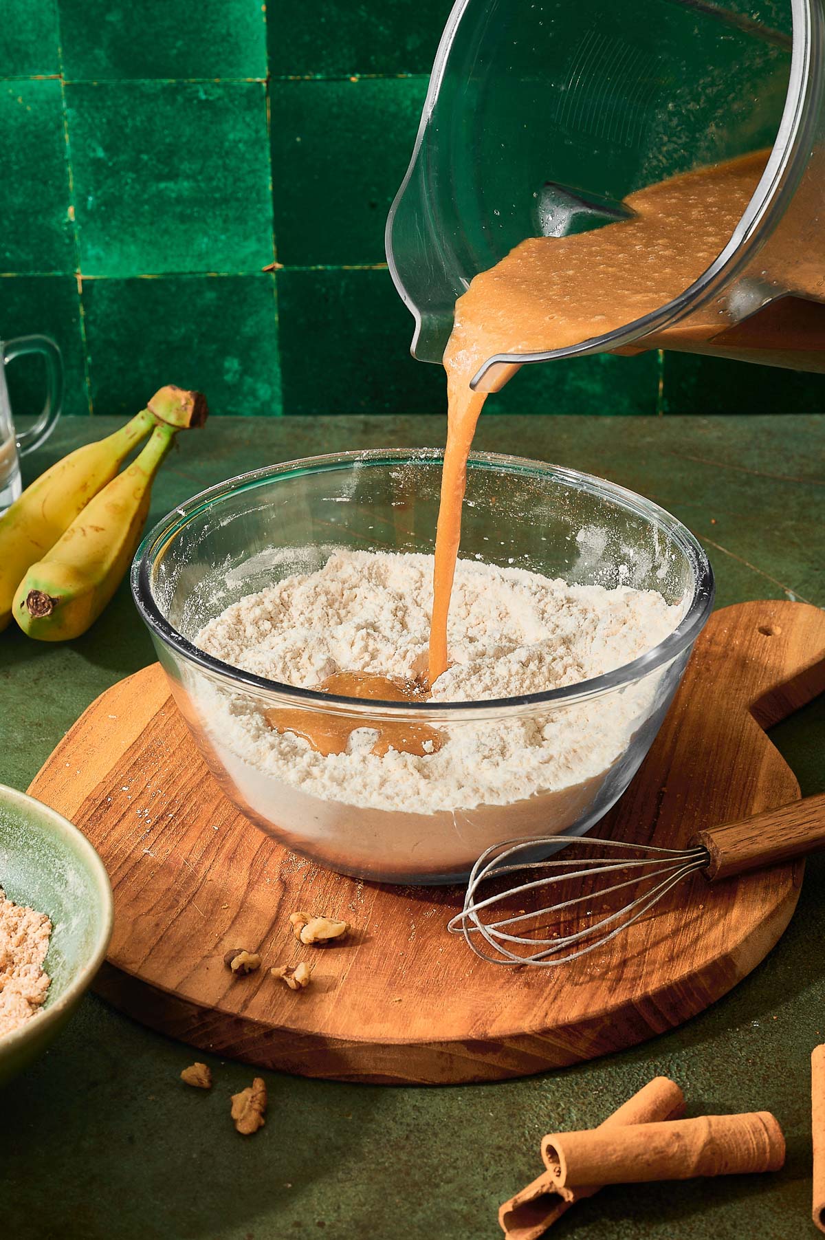 Wet muffin batter being poured into a bowl of dry ingredients