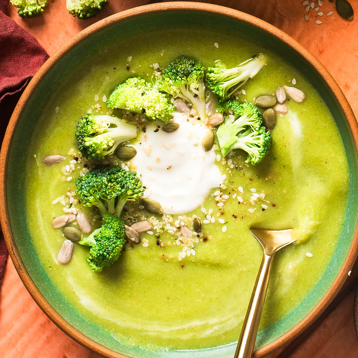 Detailed shot of creamy vegan broccoli soup topped with dairy-free sour cream, fresh broccoli, and sesame seeds.