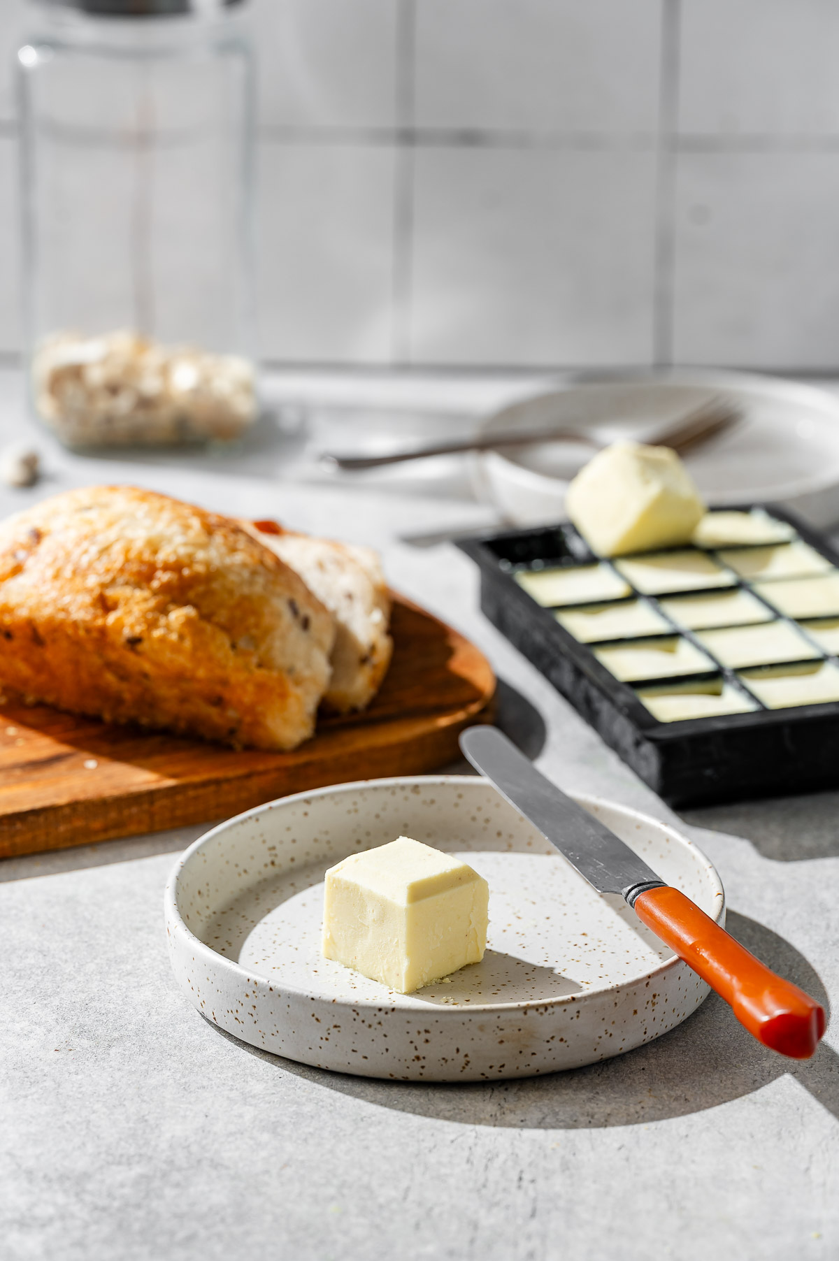 A cube of vegan butter on a ceramic plate with knife