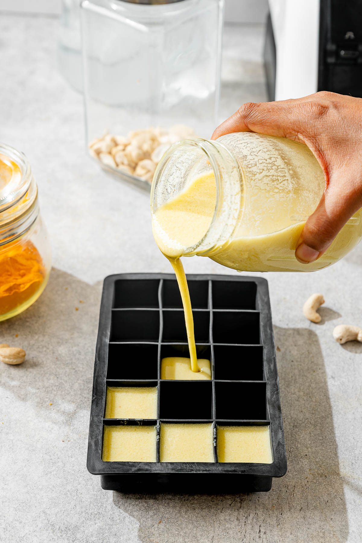 A person adding vegan butter mixture in ice cube molds
